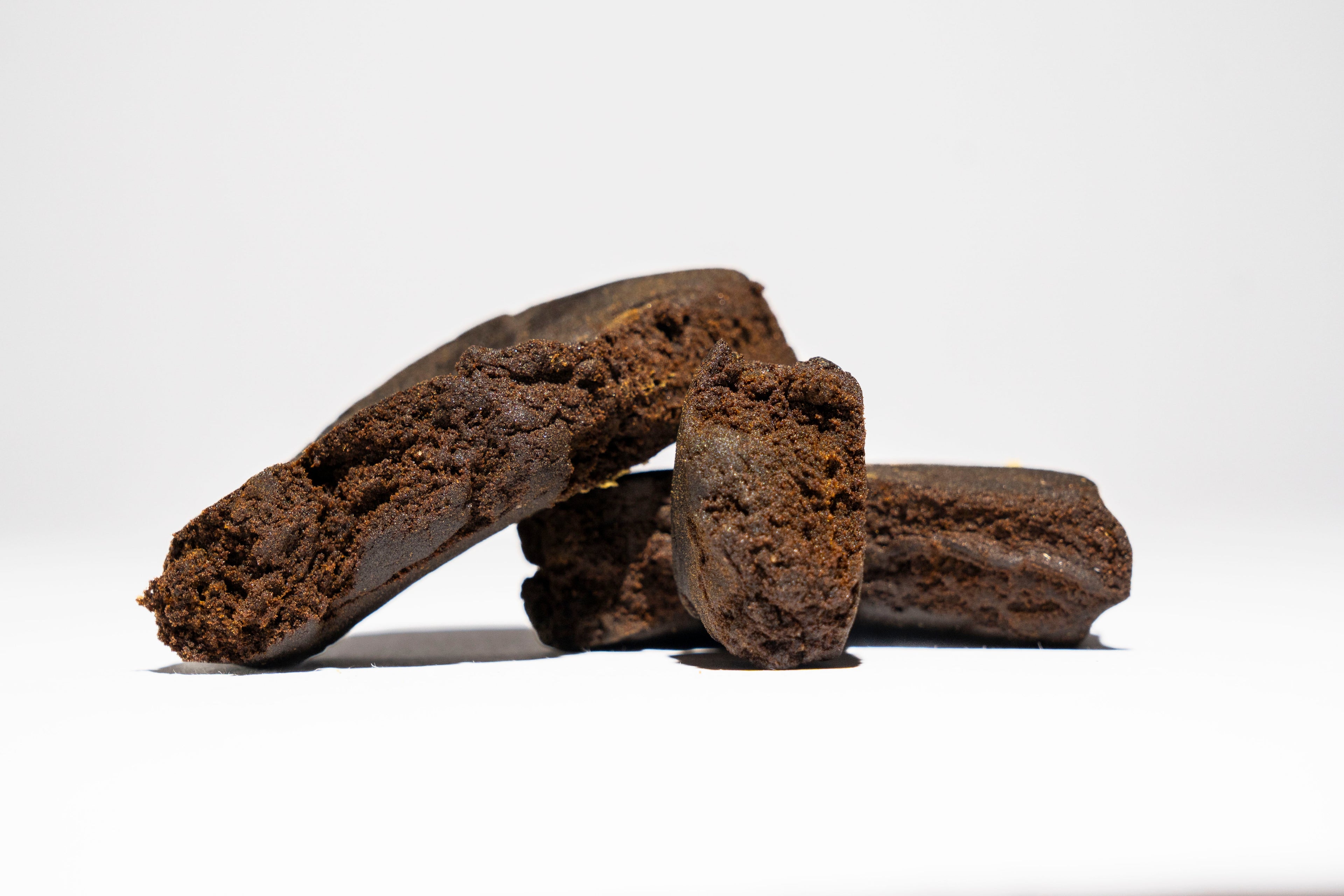 Three dark brown pieces of hash on a white background