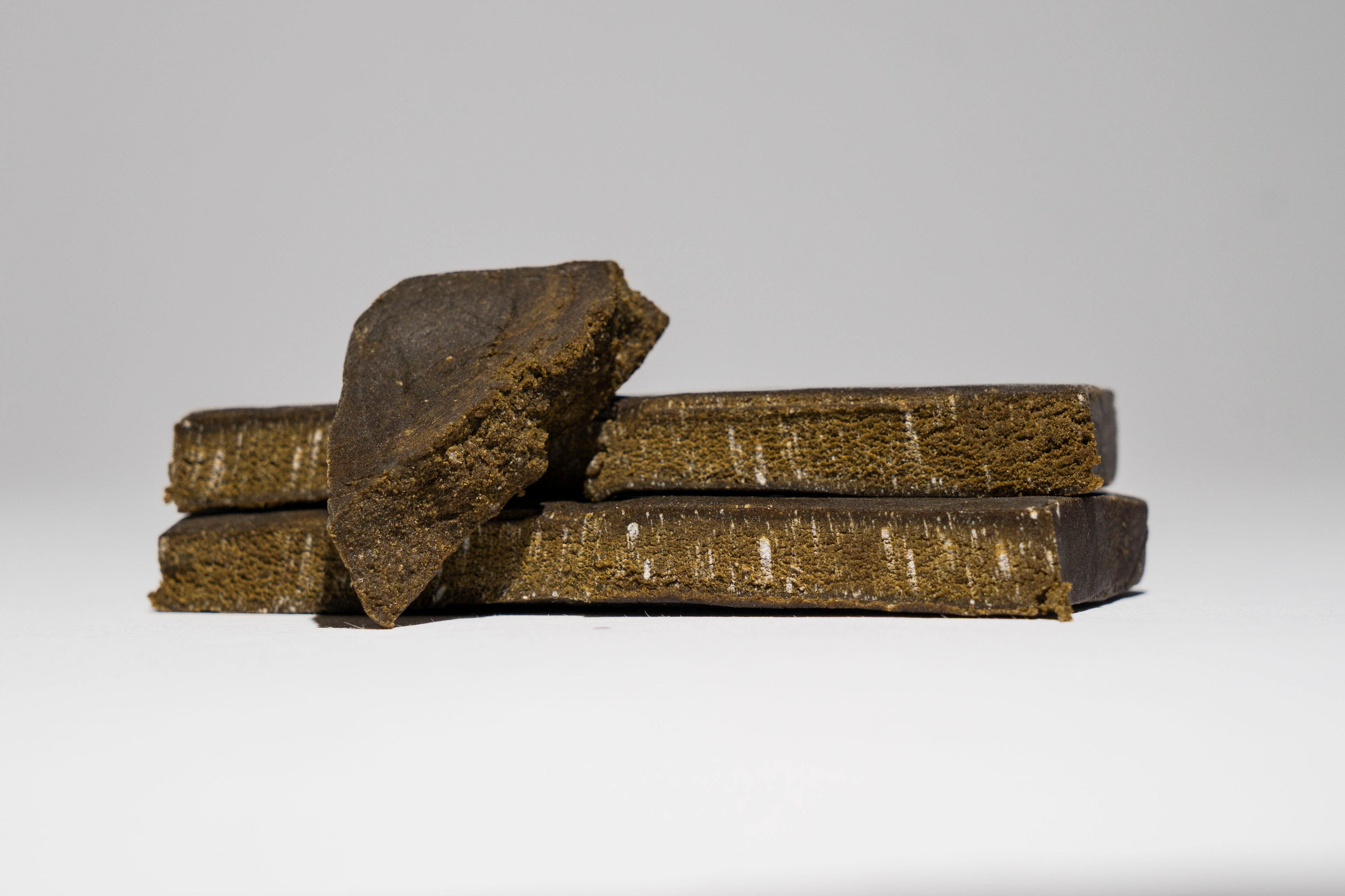 Three pieces of dark brown hash on a white background
